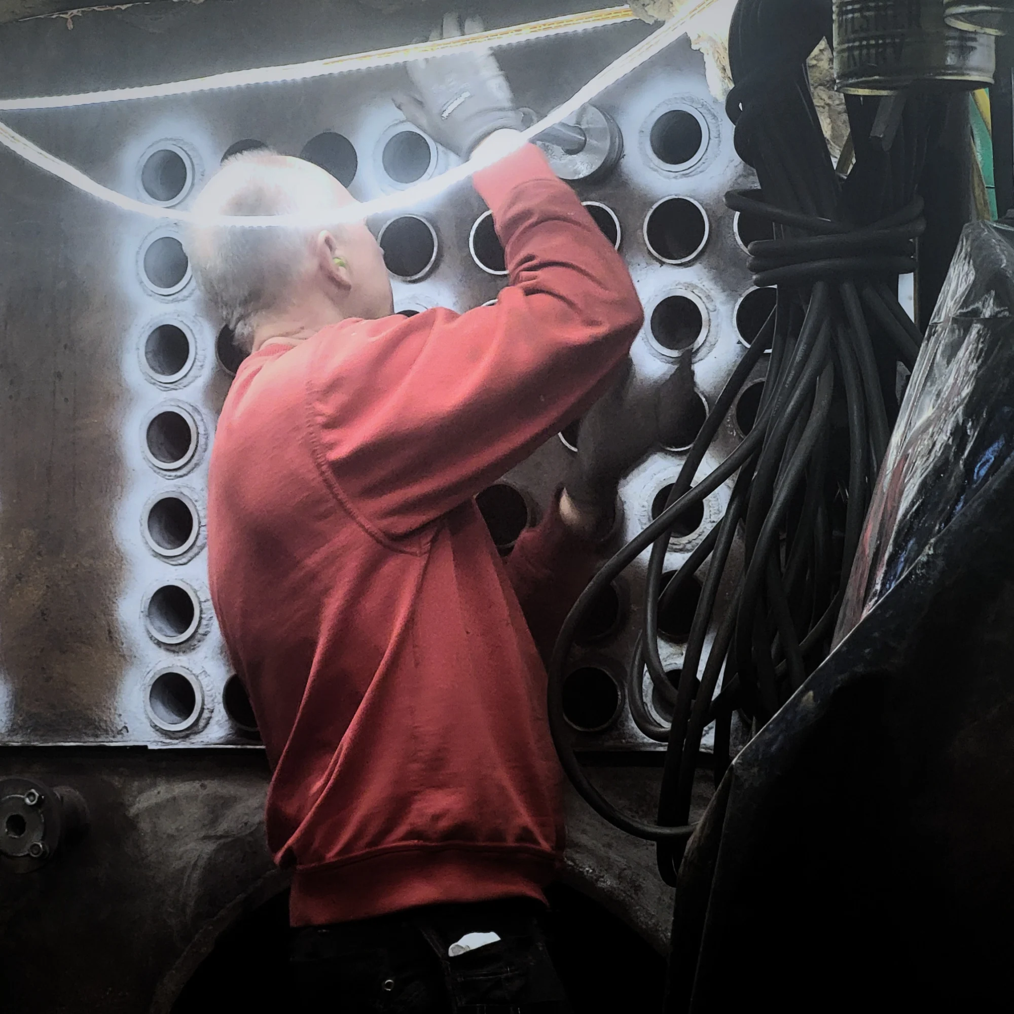 Tekniker utför tubinvalsning i ångpanna med tubvalsmaskin vid omtubning av värmeväxlare.