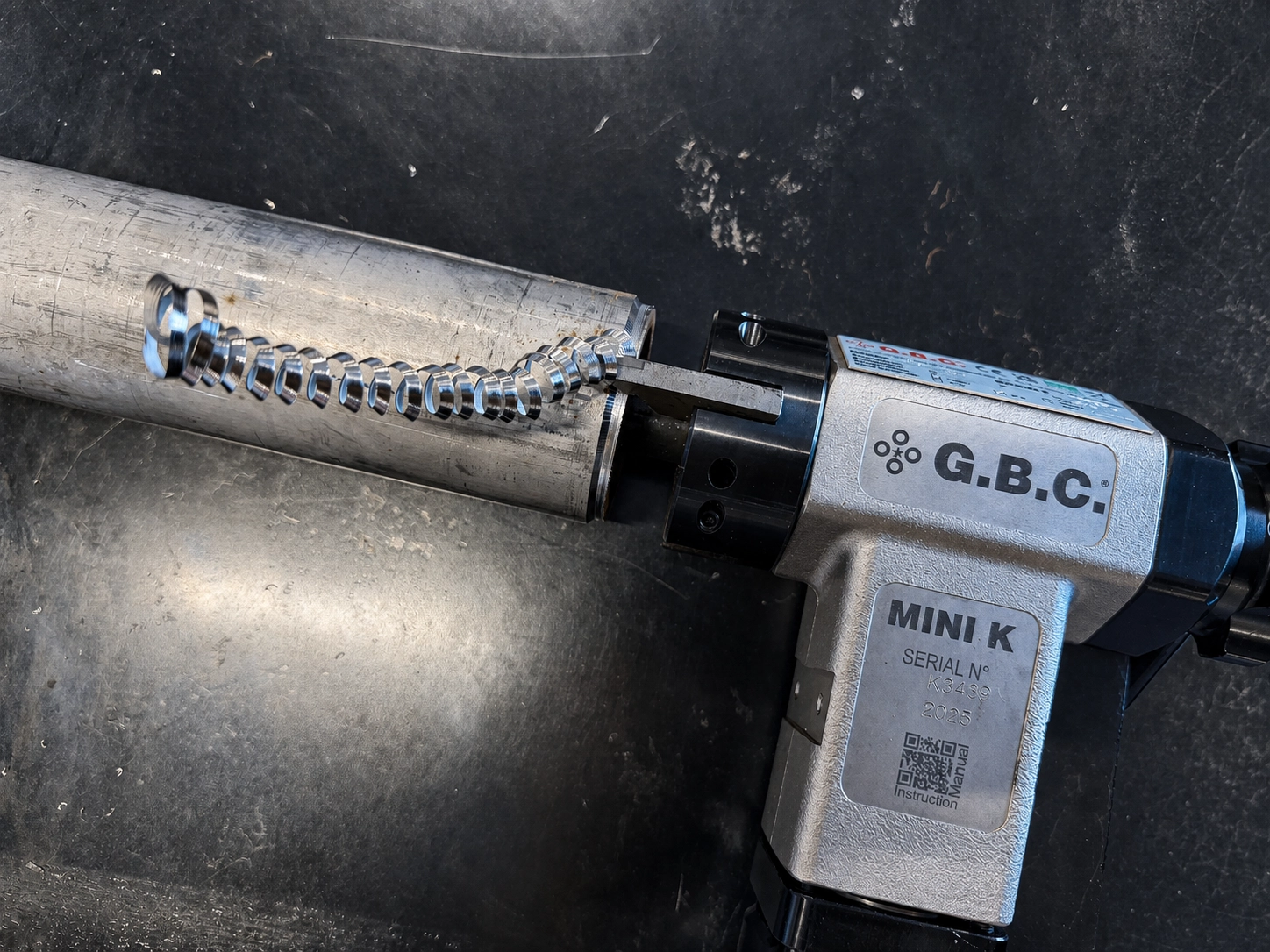 G.B.C. MINI K rörfasningsmaskin som bearbetar ett metallrör med spiralformad metallspån